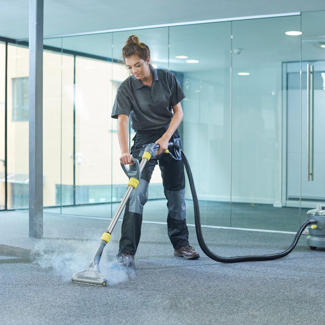 Deep Clean at Work: Steam Vacuuming for Spotless Floors A cleaning professional using a steam vacuum on a carpeted office floor, implying a deep clean with modern equipment.