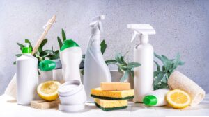 A collection of eco-friendly cleaning products, including spray bottles and natural sponges, with fresh lemons and leaves, promoting environmentally safe cleaning.
